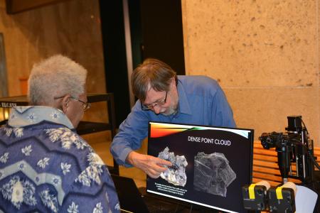 man pointing out something on computer screen to woman